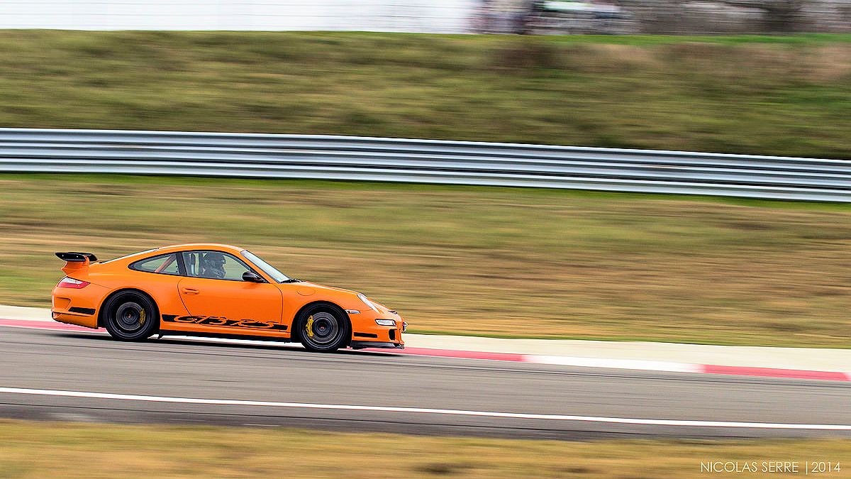 Picture of a bright orange Porsche 911 GT3 RS racing on a track